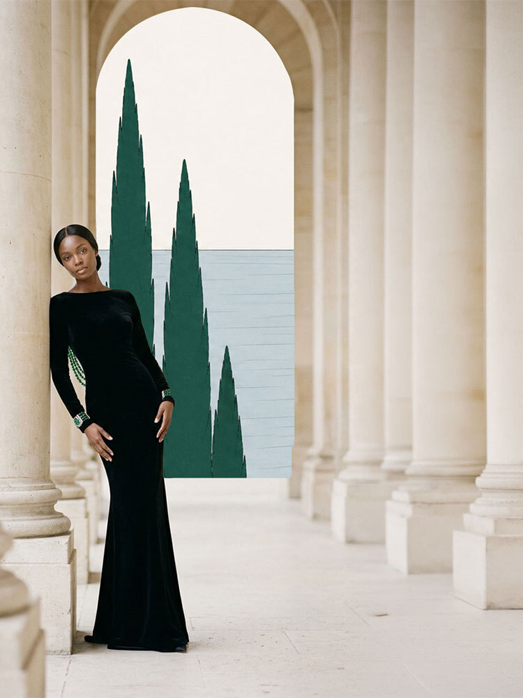 A woman in a black velvet gown leaning against a stone colonnade pillar